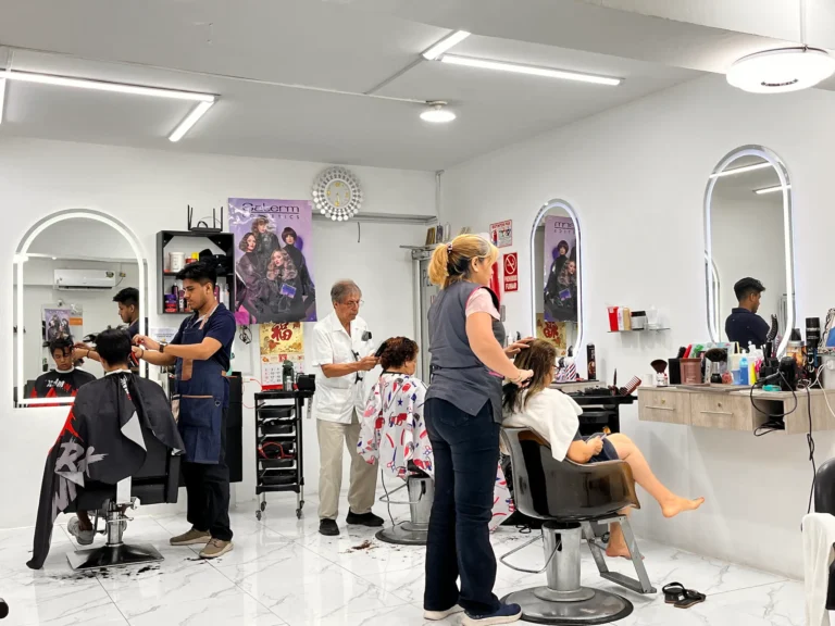 Interior de la peluquería con barberos y clientes